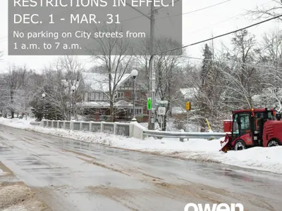 Sidewalk snow plow with words reminding people not to park overnight on the street in the winter