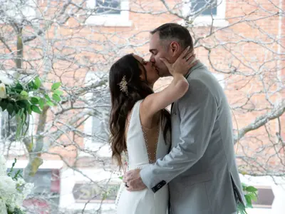 Bride and groom kissing in front of tree